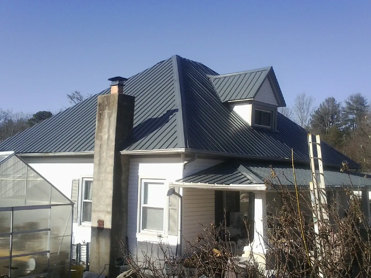Dark blue standing seam metal roof on a white farmhouse with dormer — Slate & Tile Roof Repair by Roofing Brothers in Philomath