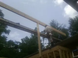 Carpenter setting a ridge beam over a new addition frame — Ice Dam Removal by Roofing Brothers in Philomath