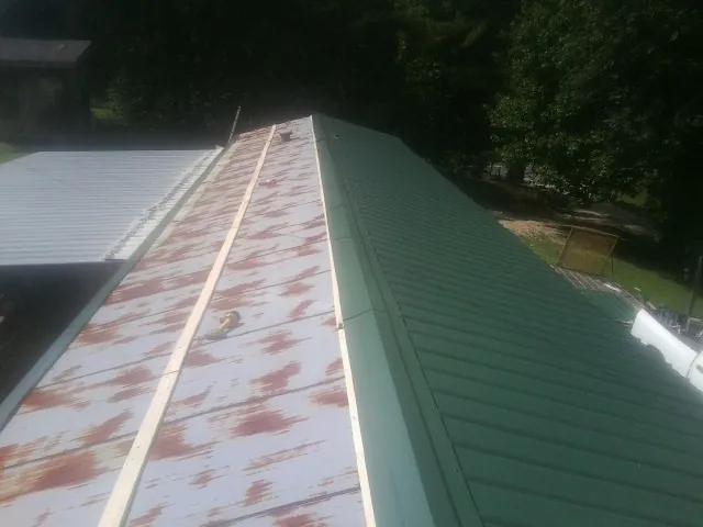 Old rusted panels beside newly installed green metal roofing — Wind Damage Roof Repair by Roofing Brothers in Philomath