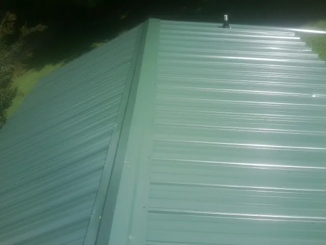 New green metal panels meeting at the ridge of a roof — Flat Roof Repair work by our crew in Philomath