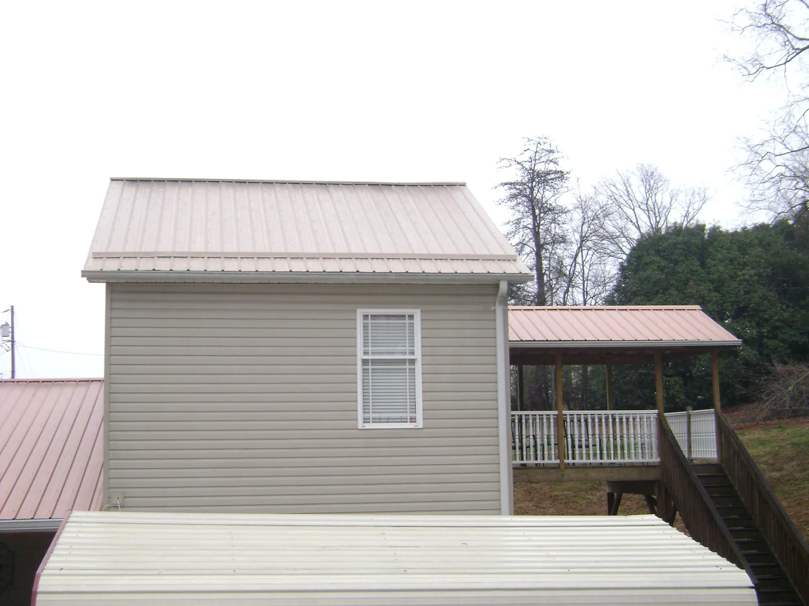 Tan metal roofs on a two story addition and attached porch, from a Roof Replacement job in Philomath