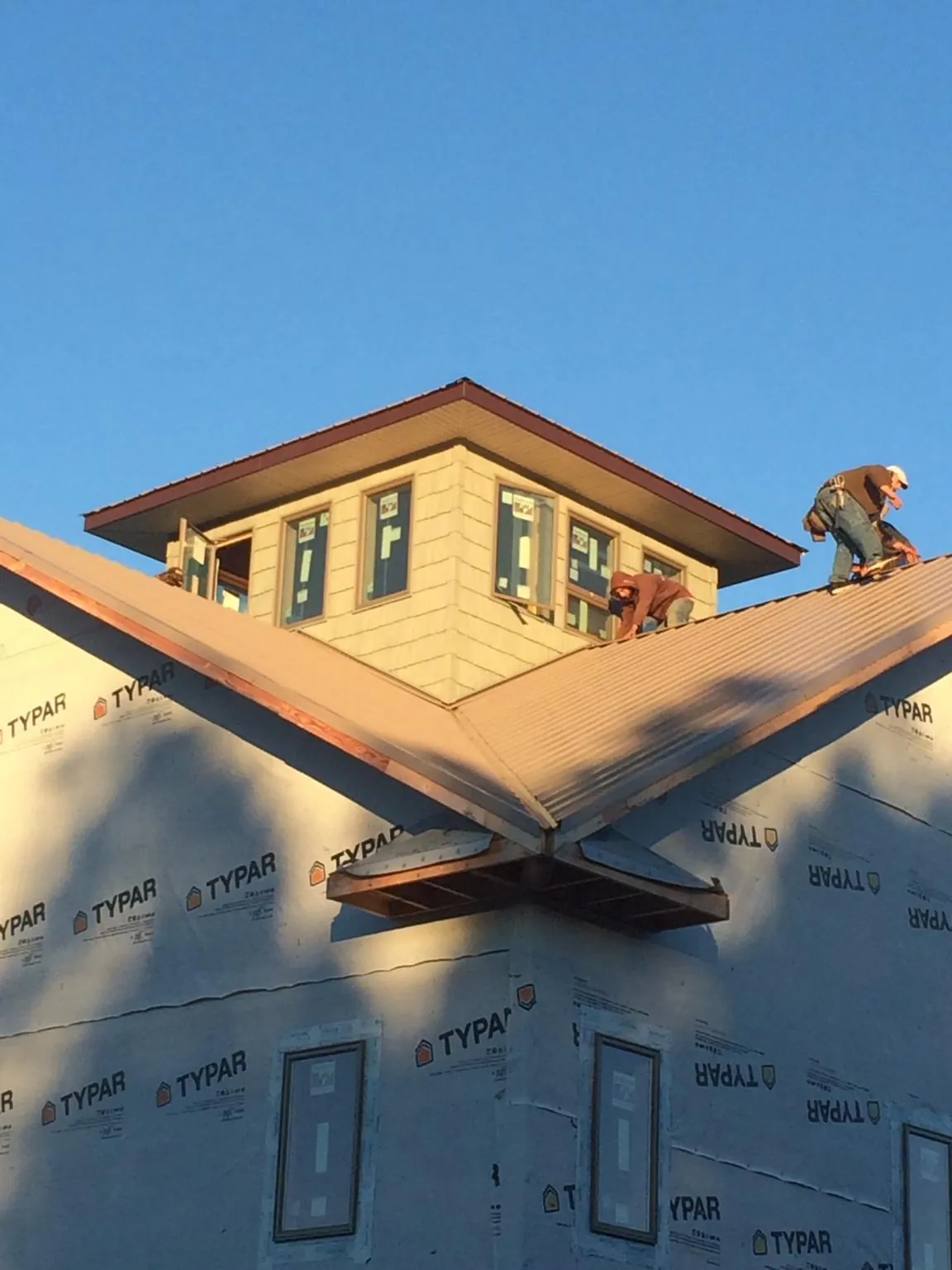 Roofers working around a rooftop cupola on a new metal roof at sunset — Roof Waterproofing in Philomath by Roofing Brothers